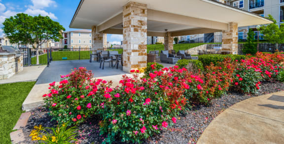 a patio with flowers and a table and chairs in front of a building