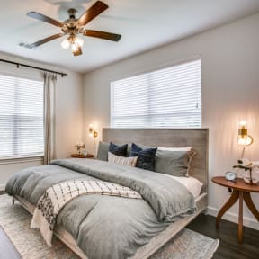 a bedroom with two windows and a ceiling fan
