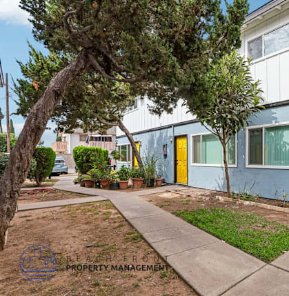 A building with a yellow door is surrounded by greenery.