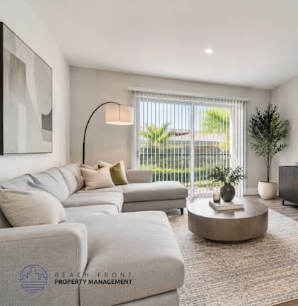 A living room with a grey sofa set, a coffee table, and a flat screen TV mounted on the wall.