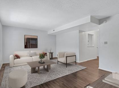 A living room with a white couch, a coffee table, and a chair.