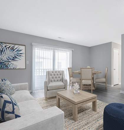 A living room with a grey couch, a coffee table, and a dining area in the background.