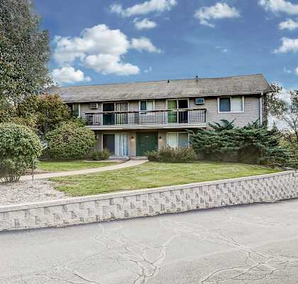 the front of a house with a yard and a stone retaining wall