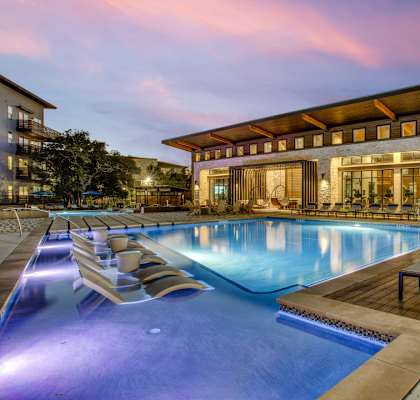 a swimming pool with chaise lounge chairs and a building in the background