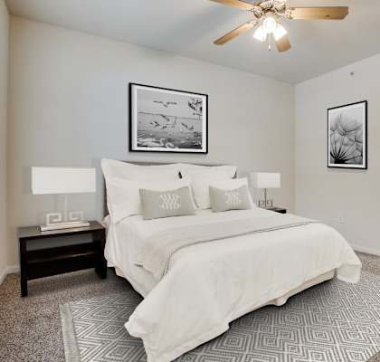 A bedroom with a large bed and a ceiling fan.