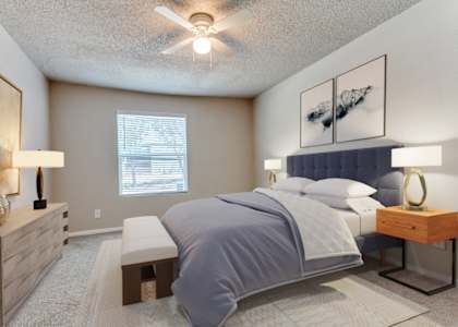 A bedroom with a large bed and a ceiling fan.
