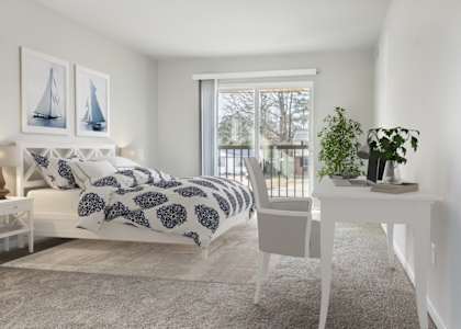 a bedroom with a bed and a white desk and a window