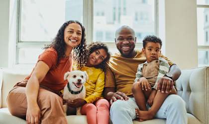 A family of four sitting on a couch with a dog.