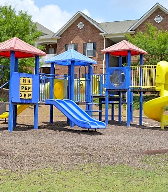 A playground with a green and yellow slide and a wooden structure.