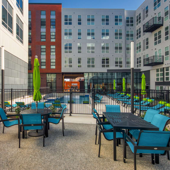 a patio with tables and chairs and a swimming pool in front of an apartment building