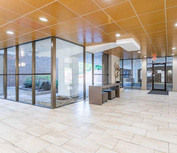 A spacious hallway with a tiled floor and glass walls leading to an outdoor area. at Charlestowne North Apartments, Maryland