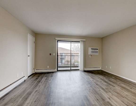 an empty living room with a sliding glass door to a balcony