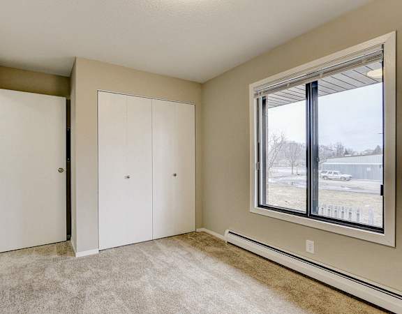 an empty bedroom with a large window and closet