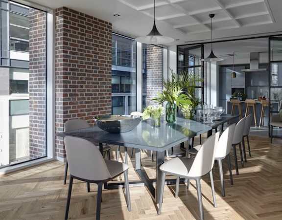 a dining room with a glass table and chairs and a brick wall
