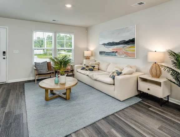 A living room with a white couch, a wooden coffee table, and a painting on the wall.