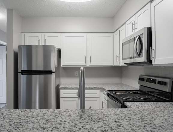 A kitchen with a refrigerator, microwave, oven, and stove.