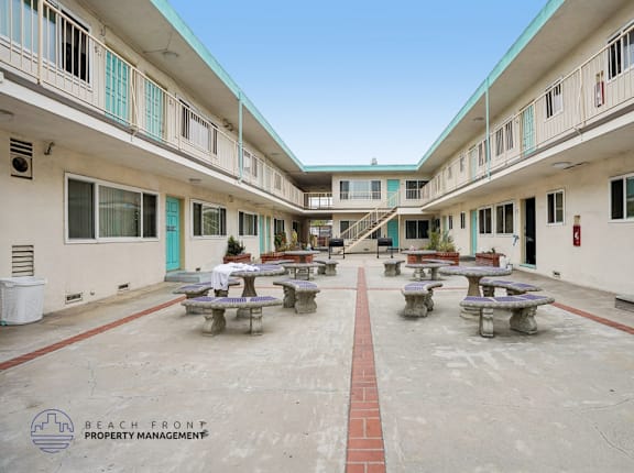 A courtyard with tables and benches surrounded by buildings.