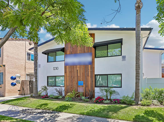 A modern house with a wooden front door and a green lawn.