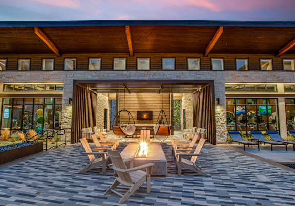 A modern outdoor seating area with a fireplace and chairs.