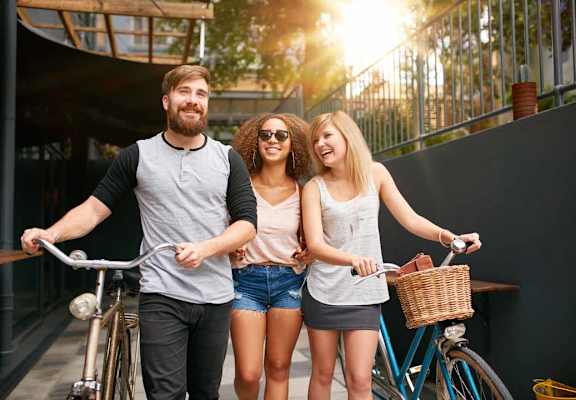 Three friends riding bicycles together on a sunny day.