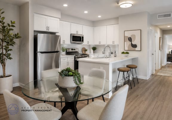 A modern kitchen with a glass table and white chairs.