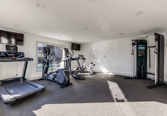 a gym with exercise equipment on the floor and walls covered in plaster