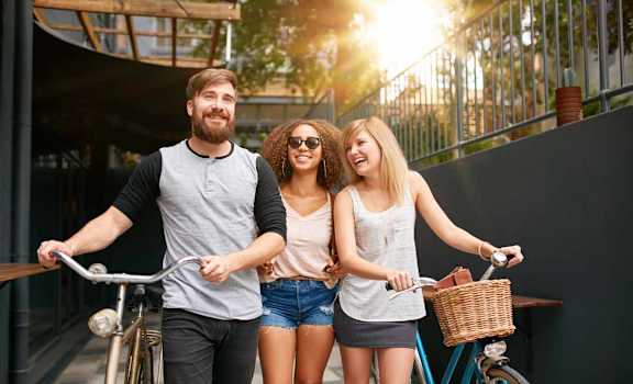 a man and two women riding bikes on a sidewalk