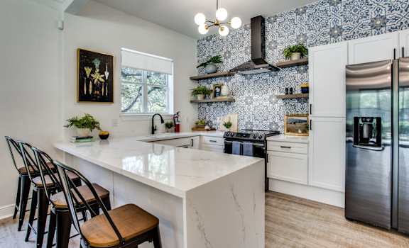 a kitchen with white cabinets and a large white island with a marble countertop