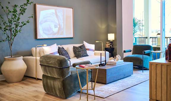 A living room with a white couch, a green chair, and a large painting on the wall.