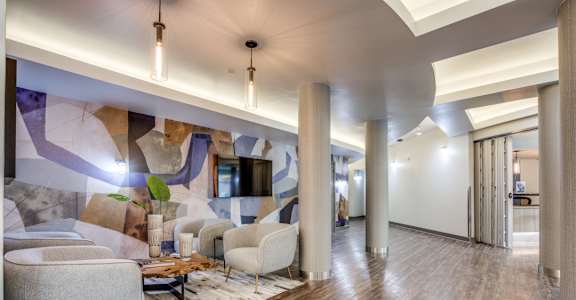 A modern living room with a wooden floor and a large mural on the wall.