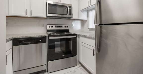 A kitchen with a stainless steel refrigerator, oven, and microwave.