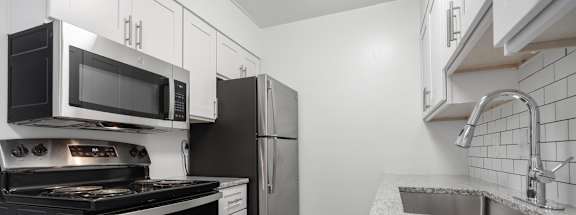A kitchen with black appliances and white cabinets.
