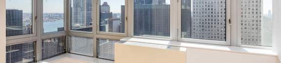 A room with a large window overlooking a cityscape. at The Metropolis, New York, NY