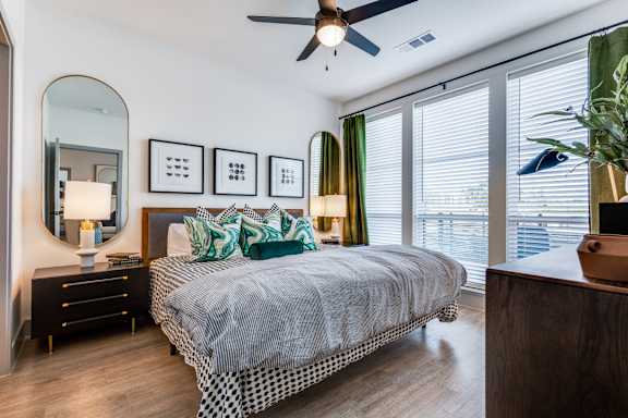 A bedroom with a bed, nightstand, and a mirror on the wall.