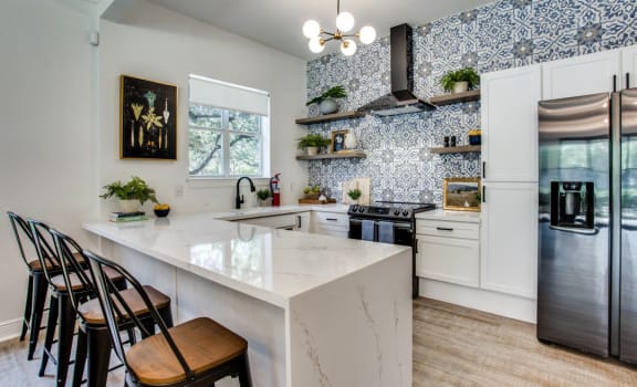 a kitchen with white cabinets and a large white island with a marble countertop