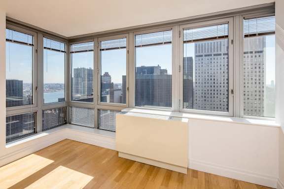 A room with a large window overlooking a cityscape. at The Metropolis, New York, NY, 10017