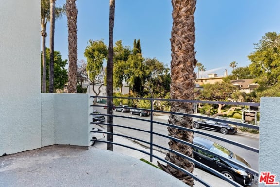 a balcony with a view of a street and palm trees