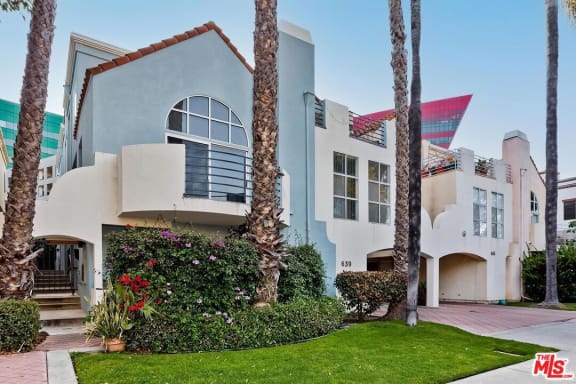 a blue and white house with palm trees in front of it
