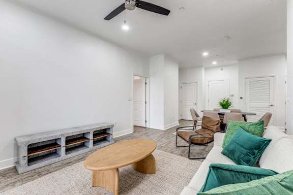 A living room with a white couch, a wooden coffee table, and a ceiling fan.