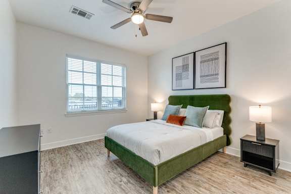 A bedroom with a bed, nightstands, and a ceiling fan.