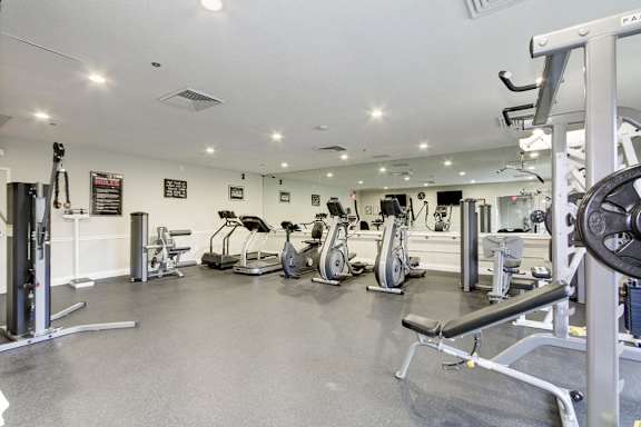 A gym with a variety of equipment including weights and cardio machines.