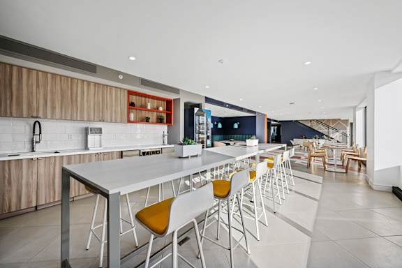 A modern kitchen with white and yellow chairs.