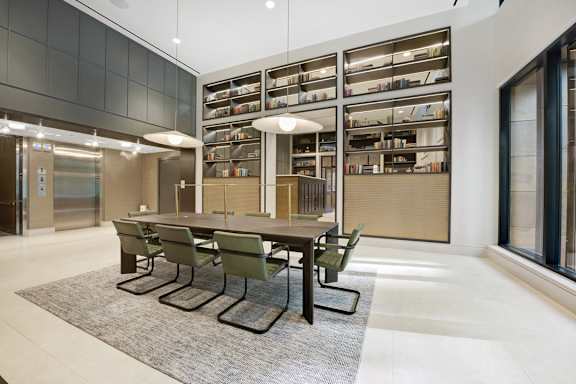 A conference room with a long table and chairs in front of a bookshelf.