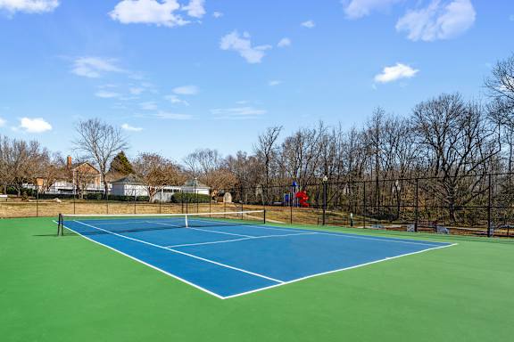 A blue and green tennis court with a white line down the middle.