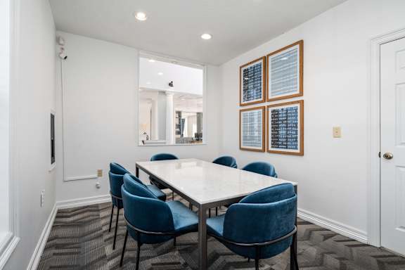A conference room with a white table and blue chairs.