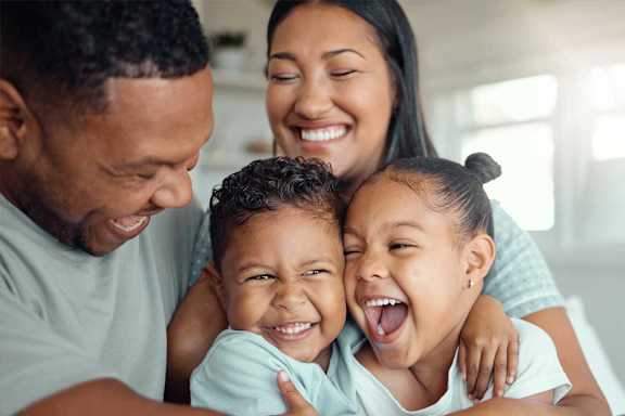 A family of three is hugging and smiling together.