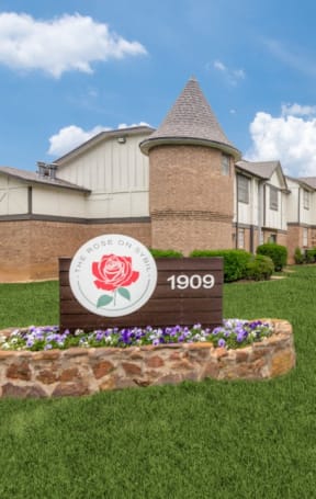 our sign in front of our building with some flowers in the grass