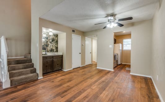 an empty living room and kitchen with a ceiling fan