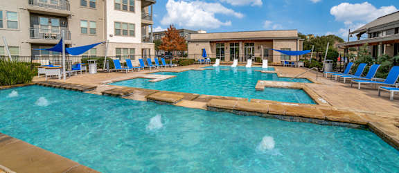 our apartments have a large swimming pool with chairs at The Landings at Brooks City-Base, Texas, 78235