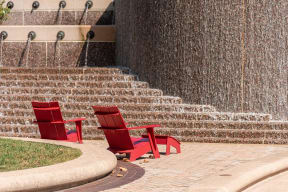two red chairs sitting in front of a water fountain
